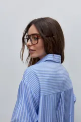 Camisa de manga larga con diseño de rayas verticales blancas y verdes, calce relajado, cuello clásico y botonadura frontal con botones perlados.