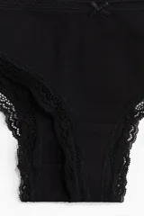 Pack de cinco bombachas estilo brazilian color negro, con ribetes de encaje y pequeño lazo decorativo en el centro de la cintura.