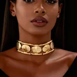 Gargantilla tipo choker ancha de color dorado, compuesta por una estructura rígida que sostiene varios discos circulares con textura martillada.