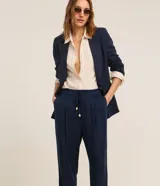 Pantalón de vestir color beige, de corte recto, con cintura elástica ajustable con lazo y bolsillos laterales.