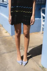 Minivestido negro tejido con lurex, escote redondo y falda con volados. Presenta líneas horizontales de colores azul, amarillo, verde y fucsia.