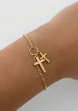 Pulsera de cadena fina dorada con dijes colgantes en forma de cruz.