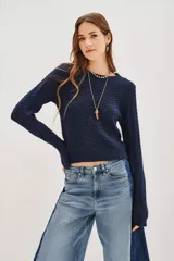 Sweater de punto en color azul marino con textura de ondas y destellos de lentejuelas integradas. Presenta cuello redondo, mangas largas y un corte ligeramente cropped.