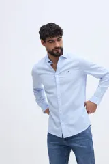 Camisa de manga larga con mezcla de lino y algodón, color celeste, de corte semi slim y cuello clásico. Cuenta con cierre frontal de botones y sutil bordado del logo de la marca en el pecho.