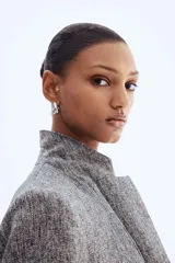 Blazer largo de corte recto con solapas de muesca, cierre frontal de un botón y bolsillos delanteros ribeteados. Presenta hombreras, pinzas en la cintura y mangas tres cuartos con diseño fruncido. Incluye forro interior.