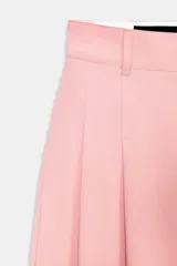 Pantalón ancho de tiro medio, color rosa pálido, con pinzas delanteras y bolsillos laterales y traseros.