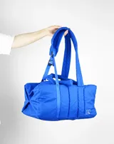 Bolso tipo tote color beige con diseño acolchado y doble asa de hombro.