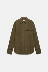 Camisa fluida de mujer de la ZW Collection de Zara, confeccionada en mezcla de viscosa, con diseño a rayas en tonos verde militar y marrón oscuro. Presenta cuello solapa, manga larga con puños anchos terminados en ribete negro a contraste, bolsillo de parche en el pecho con ribete a juego, bajo redondeado y cierre frontal con botones oscuros.