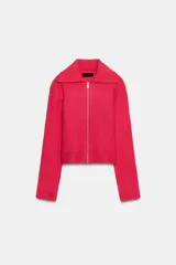 Chaqueta de punto color fucsia, con cuello solapa, manga larga y cierre frontal con cremallera metálica. Presenta puños y ruedo acanalados.