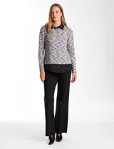 Buzo de tejido fino con efecto melange en tonos tierra, que incorpora cuello y ruedo inferior en tela tipo gasa negra, simulando una camisa debajo. Posee mangas largas y un diseño de corte recto.