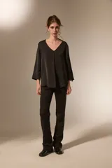 Blusa de satén color bordó con cuello en V y mangas tres cuartos. Presenta un diseño holgado con un pliegue central en el frente.