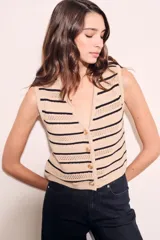 Chaleco de punto color beige con rayas horizontales negras, escote en V y cierre frontal con botones.