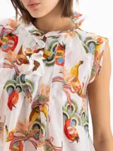 Blusa Pop de voile de seda y algodón, color blanco con estampado exclusivo de motivos frutales y florales. Presenta silueta en línea A, calce holgado, cuello alto fruncido con volados y escote profundo con volados caracol al frente.