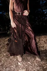 Cinturón artesanal de cuero color chocolate con hebilla cuadrada metálica y flecos largos que cuelgan a lo largo de la falda.