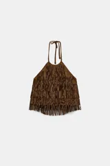 Top de cuello halter con lazada, confeccionado en tejido efecto ante. Presenta un diseño cubierto de flecos con tachas aplicadas en toda la superficie.