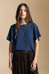 Top de color azul, con escote redondo a la base y mangas cortas amplias con caída fluida. Presenta una silueta relajada y un diseño minimalista.
