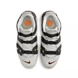 Championes Nike Air More Uptempo 96 de color blanco, negro y gris, con detalles en naranja y rojo. Presentan el característico diseño con las letras "AIR" sobredimensionadas en los laterales, suela de goma con amortiguación visible y un estilo urbano robusto.