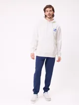 Babucha jogger color gris oscuro, con cintura elástica ajustable con cordón, bolsillos laterales y puños elásticos en los tobillos. Presenta un logo estampado en el muslo izquierdo.