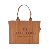Cartera tipo tote de cuero granulado en color gris, con diseño estructurado y asas superiores. Presenta el logo estampado en el frente con la inscripción The Tote Bag Marc Jacobs.