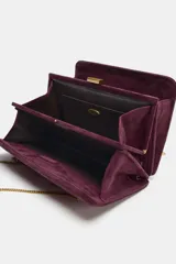 Bolso de hombro rígido de piel color bordó, con diseño de pespuntes, triple compartimento y cierre magnético. Cuenta con doble asa de cadena metálica dorada.