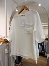 Blusa de lino color blanco, con escote redondo, mangas cortas amplias, calce relajado y un bolsillo delantero con detalle de lentejuelas.