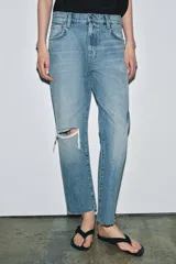 Jeans de tiro medio con corte recto y largo al tobillo. Presentan diseño de cinco bolsillos, cierre frontal con cremallera y botón, y ruedo deshilachado.