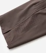 Bermuda deportiva gris con cintura elástica, cordón de ajuste, bolsillos con cremallera, recorte lateral con agujeritos y abertura en el bajo.