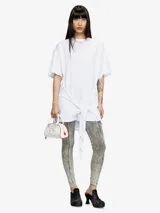 Vestido blanco de manga corta, estilo camiseta, confeccionado en jersey de algodón orgánico. Presenta un lazo frontal ajustable que genera un efecto drapeado y un recorte bordado en el frente.