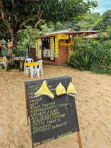 Bombacha de bikini negra con ribetes en color amarillo pastel. Presenta tiras laterales finas ajustables y una pequeña placa metálica decorativa con el nombre de la marca en la parte superior.