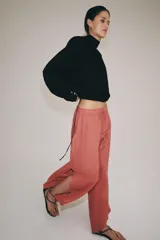 Pantalón confeccionado en lino 100%, de tiro medio con cintura elástica ajustable mediante cordones y bajo redondeado con aberturas laterales.