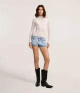 Short micro de jean celeste de tiro bajo, con bolsillos, trabillas y detalle de cadenita colgante de estrellas en la presilla.