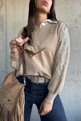 Sweater de punto color beige, con cuello redondo y mangas largas abullonadas. Presenta detalles bordados con lentejuelas y perlas en los hombros y parte superior de las mangas.