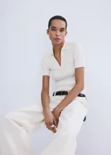 Chaleco de tejido de punto fino y diseño entallado, con cuello camisero, escote en V y mangas cortas.