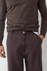 Pantalón estilo skater de corte holgado, color marrón oscuro, con cierre de botón y cremallera, bolsillos laterales y traseros.