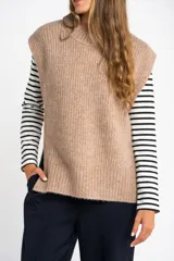 Chaleco de punto color beige con cuello alto y sisas amplias.