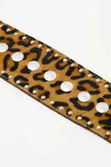 Cinturón tipo faja de cuero vacuno con estampado animal print, decorado con tachas metálicas plateadas y tiras laterales con borlas decorativas.