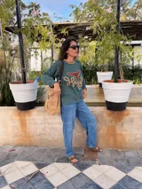 Sweater verde tejido con cuello redondo y diseño de cabeza de vaca en cuero marrón con bordados a mano en color beige.