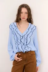 Blusa rosada de manga larga con escote en V, volados frontales con ribete negro contrastante y puños elásticos.