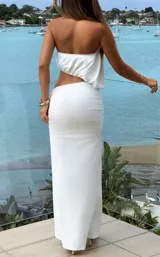 Set de dos piezas color blanco compuesto por un top halter sin mangas de corte fluido y una pollera larga con fruncidos en la cintura.