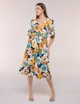 Vestido midi de calce holgado y caída fluida con escote en V cruzado, cintura elastizada fruncida y mangas cortas con volados superpuestos. Cuenta con un diseño estampado de flores grandes en tonos amarillo, blanco, azul marino y verde.