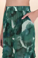 Pantalón ancho de tiro alto con cintura elástica y bolsillos cargo a los lados. Confeccionado en tela ligera con estampado abstracto en tonos verdes y azules.