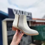 Bota urbana de cuero bicolor en tonos blanco y gris, con taco de madera y cierre lateral.
