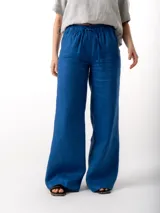 Pantalón de lino azul con corte amplio, cintura elastizada con cordón ajustable, dos bolsillos laterales y un bolsillo trasero.