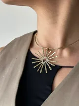 Gargantilla dorada con dije en forma de sol con rayos texturizados.