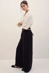 Pantalón negro de corte ancho y relajado, con tiro alto y bolsillos laterales.