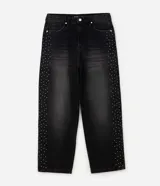 Pantalón de jean super baggy color negro con lavado oscuro y efecto deslavado, con tachas metálicas aplicadas en los laterales de las piernas.