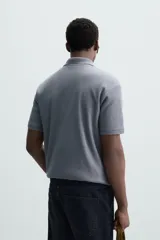 Polo de manga corta color verde oliva, con cuello solapa y abertura frontal tipo polo. Presenta una textura acanalada vertical y un calce regular.