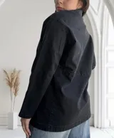 Sobrecamisa negra de jean con cuello camisero, cierre frontal con botones metálicos, bolsillos de parche en el pecho y corte recto.