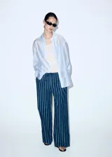 Pantalón de corte recto y tiro regular, confeccionado en algodón con diseño de rayas verticales. Presenta cintura elástica con cordón ajustable y bolsillos laterales.