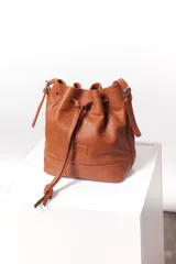 Cartera tipo botellero color marrón con efecto trenzado, tamaño mediano, cierre con frunce, correa ajustable con hebilla para usar al hombro o cruzada, doble bolsillo interior (uno con cierre).